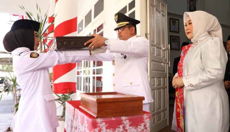 PJ Bupati Bantaeng, DR. Andi Abubakar, S.Ip., M.Si didampingi PJ Ketua TP PKK Kabupaten Bantaeng, Andi Raodhayanti menyerahkan Bendera Merah Putih kepada Paskibrakan untuk di kibarkan pada Upacara HUT Proklamasi ke-79 di Tribun Seruni Bantaeng. (17 Agustus 2024).